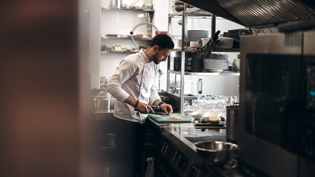 A chef arranging knives and tools on a clean stainless prep station